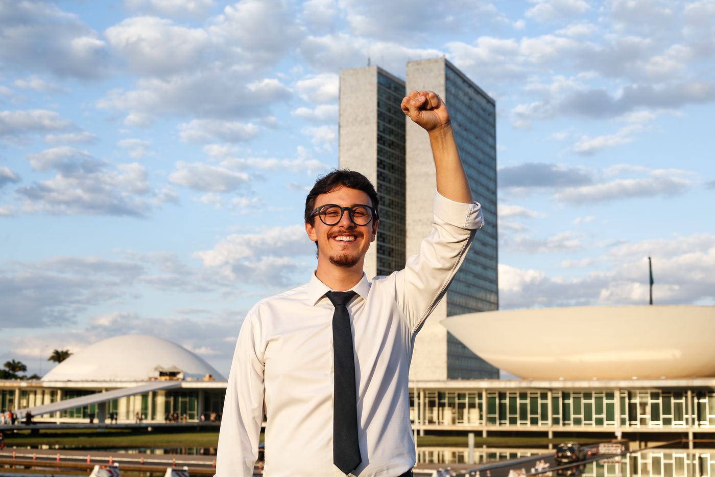 Guilherme Cortez com o punho erguido em frente ao Congresso Nacional, em Brasília